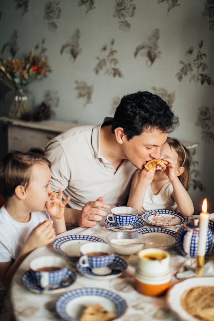 The Art of Drawing Readers In: Your attractive post title goes here A father and his two children share a joyful meal featuring traditional crepes, creating a warm family moment indoors.