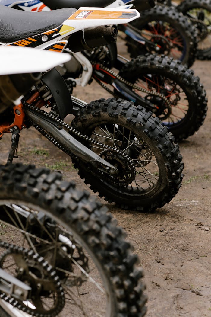 Mastering the First Impression: Your intriguing post title goes here Close-up of dirt bikes parked on muddy ground, showcasing tires and chains.